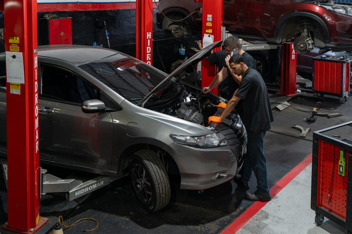 Equipe da Tetemann trabalhando em um Honda City sobre o elevador, com bancadas vermelhas ao lado